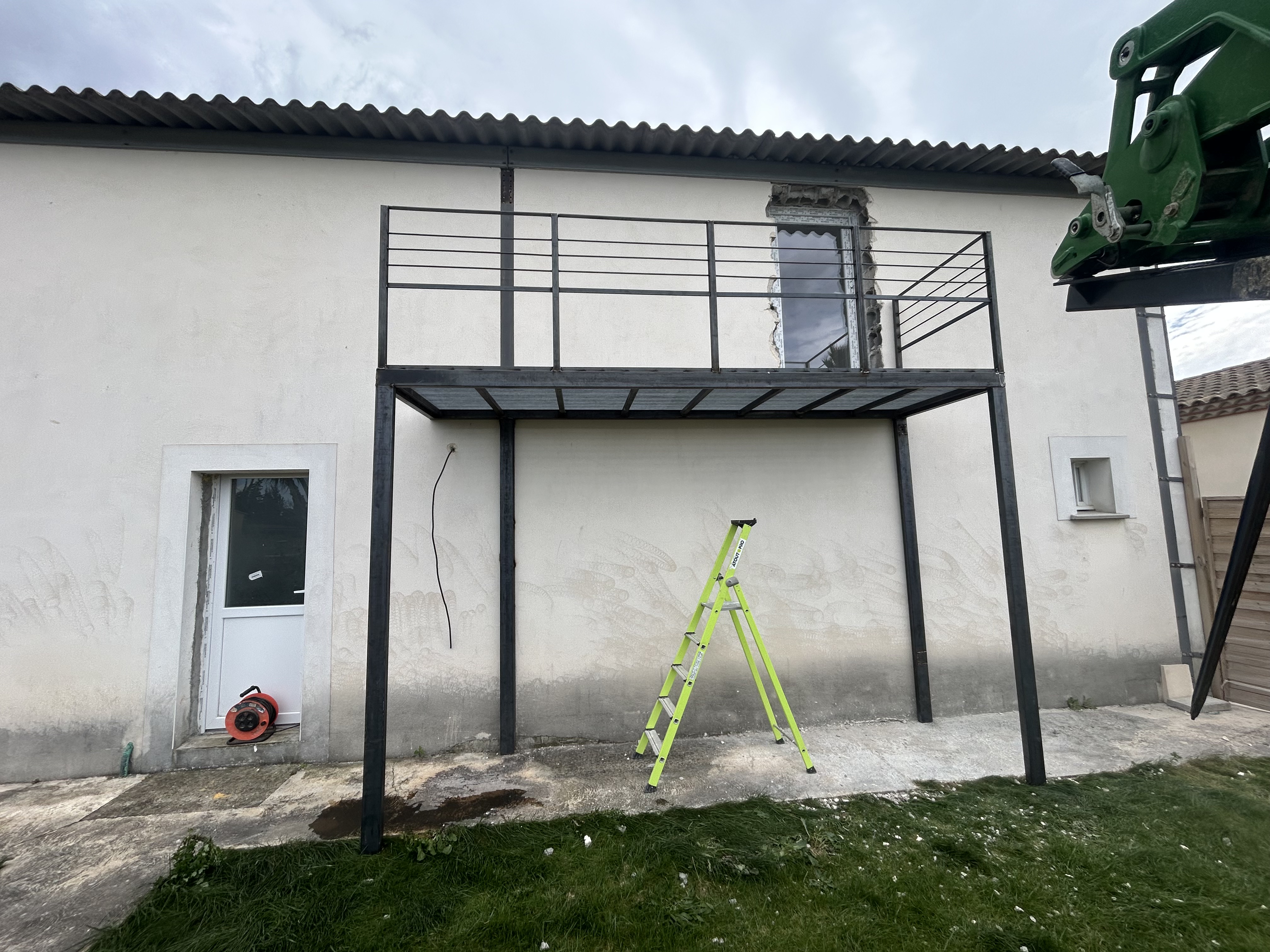 Pose d'une structure métallique autoportée sur façade de maison pour création de terrasse suspendue.